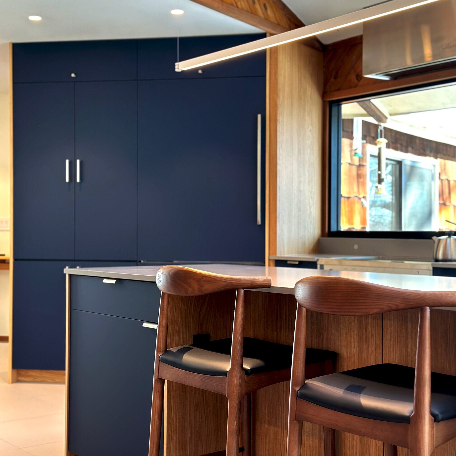 Modern Blue Oak Kitchen with deep navy cabinetry, oak wood accents, minimalist island seating, and contemporary linear lighting design