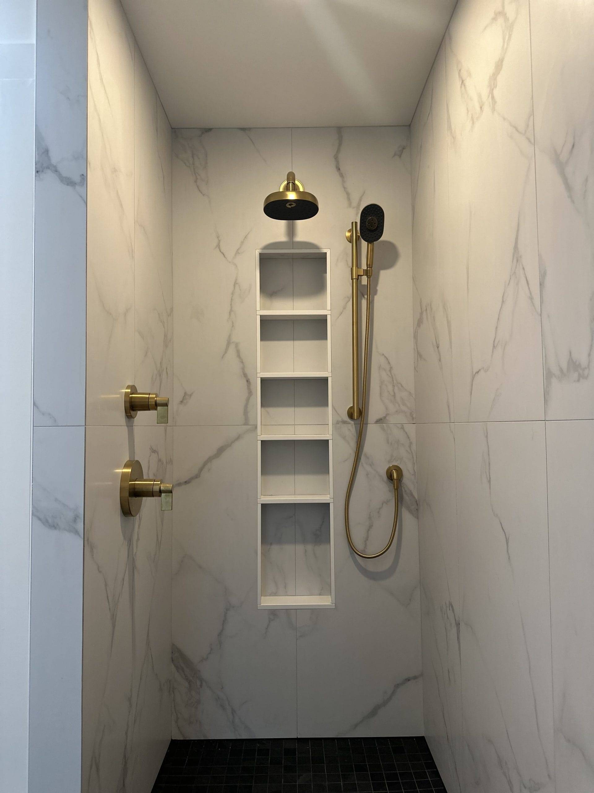 bathroom with marble walls and golden showerhead
