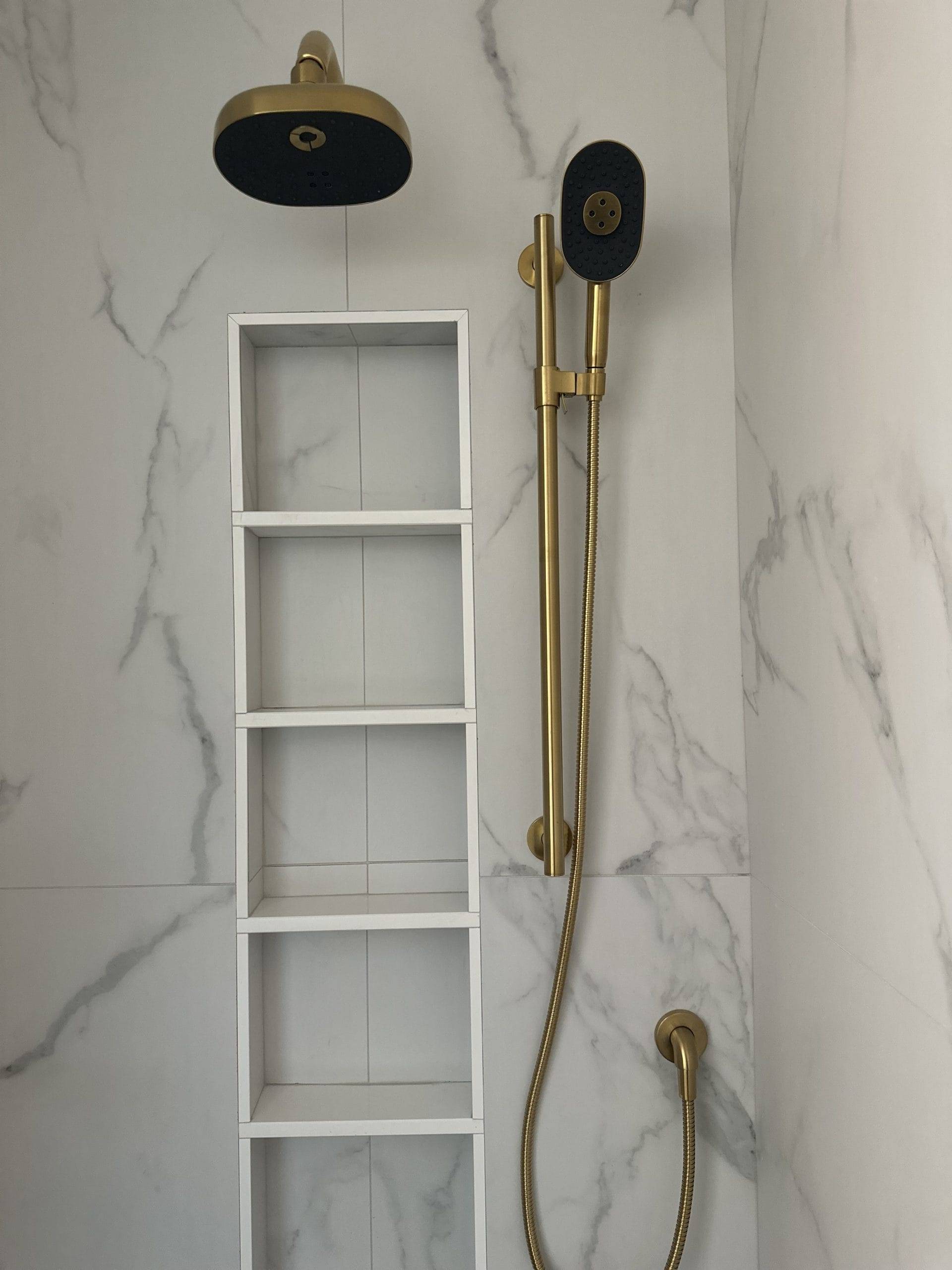 bathroom with marble walls and golden showerhead